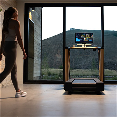 Model approaching the NordicTrack Ultra 1 Treadmill in a home gym