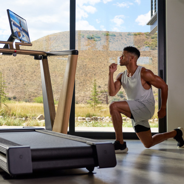 Model performing a forward lunge beside the NordicTrack Ultra 1 Treadmill