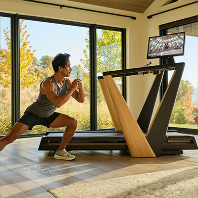 Model performing a side lunge beside the NordicTrack Ultra 1 Treadmill  