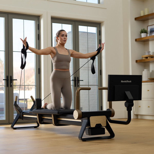Model doing resistance arm extension on the NordicTrack Ultra 1 Reformer