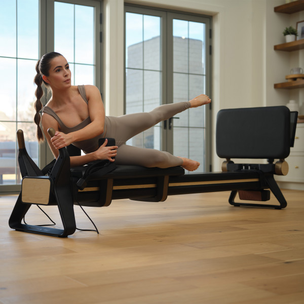 Model doing side leg lift on the NordicTrack Ultra 1 Reformer