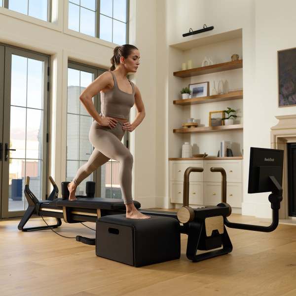 Model doing step-up exercise on the NordicTrack Ultra 1 Reformer