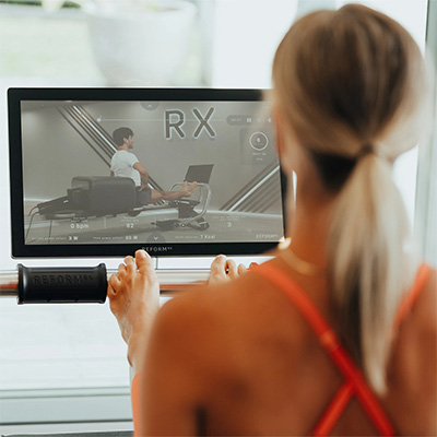 Rear view of user engaging with the touchscreen console during workout on the NordicTrack Ultra 1 Reform RX-S  