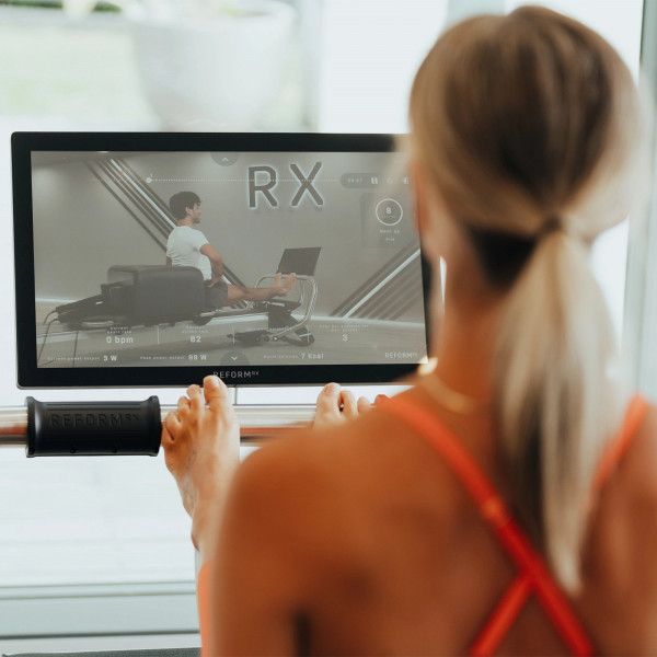 Rear view of user engaging with the touchscreen console during workout on the NordicTrack Ultra 1 Reform RX-S