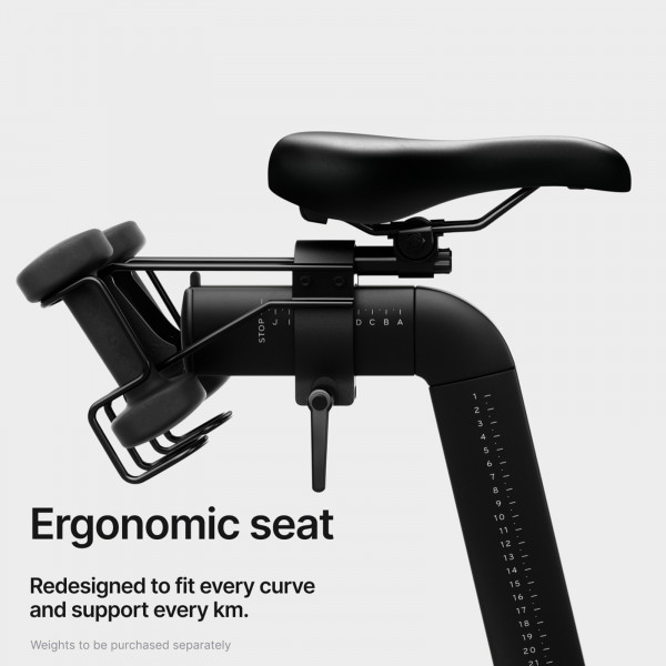 An infographic stating: Ergonomic seat. Redesigned to fit every curve and support every km. A subtext states: "weights to be purchased separately." The Peloton Bike Dumbbell Pairs are available at Fitshop.