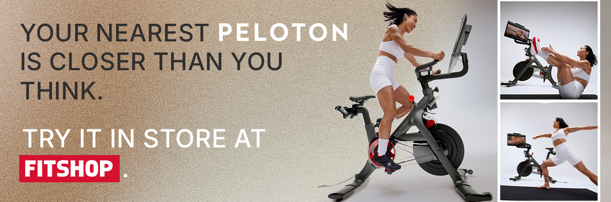 Person cycling on the Peloton Cross Training Bike+ next to Fitshop in-store promotional messaging