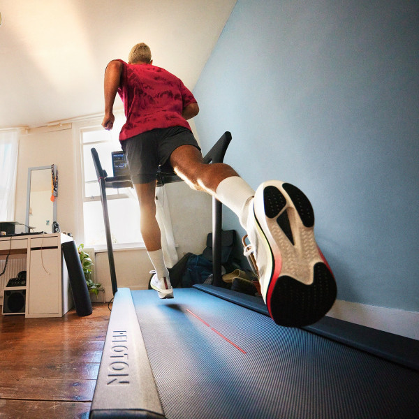 Rear view of a person running on the Peloton Original Series Tread in a bright room