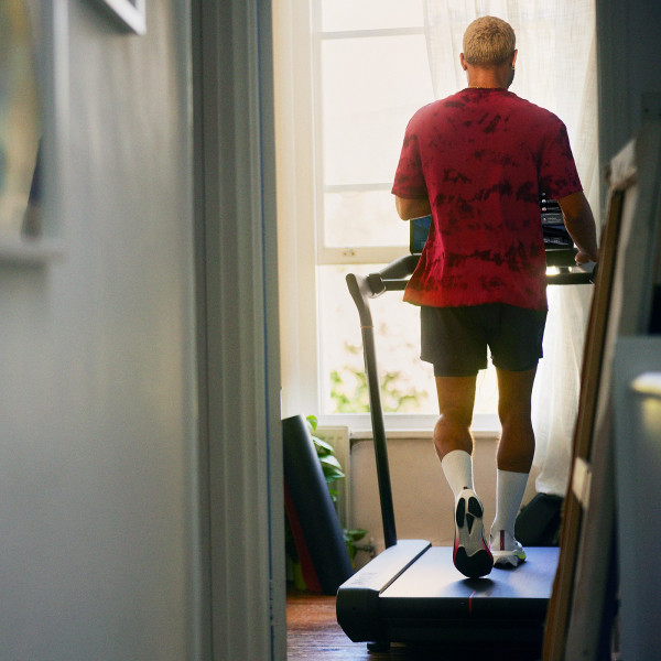 Rear view of a person using the Peloton Original Series Tread near a window