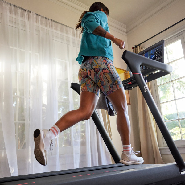 Side-angle view of a person jogging on the Peloton Original Series Tread