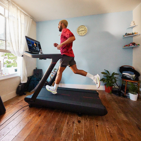 Side view of a person running on the Peloton Original Series Tread in a home setup
