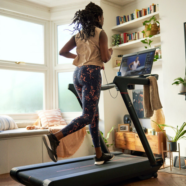 Person mid-run on the Peloton Original Series Tread with workout metrics onscreen