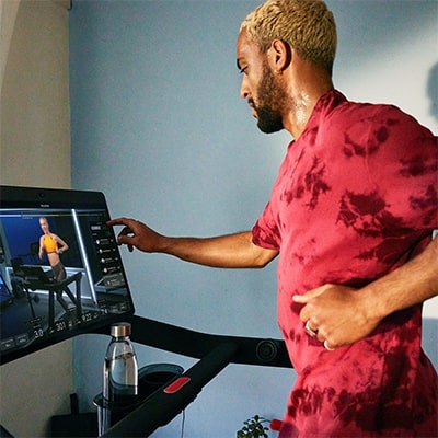 Person using the Peloton Original Series Tread while following a guided workout on the touchscreen