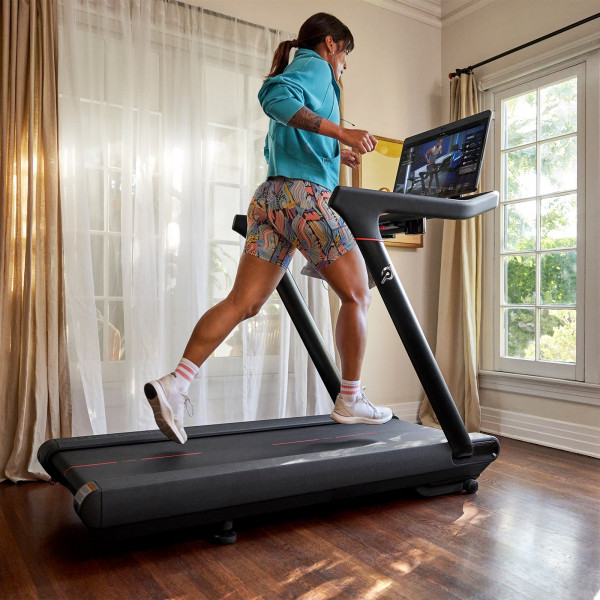 Wide shot of a person running on the Peloton Original Series Tread in a bright home