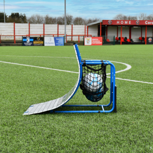 PrecisionPLAY Skills Trainer Ramp Rebounder set up on a football pitch with ball storage net
