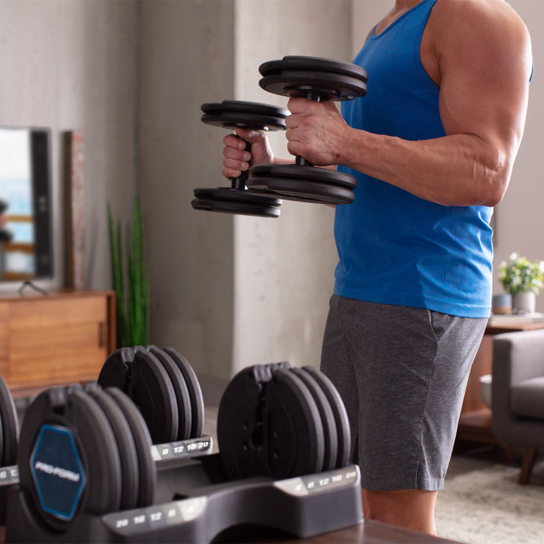 A model standing with the Proform 20kg Adjustable Dumbbells