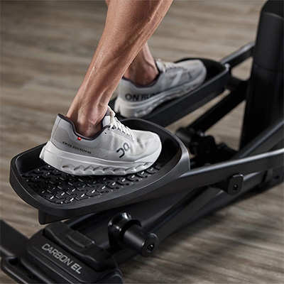 Close-up of the ProForm Carbon EL Elliptical textured pedals with model wearing trainers  