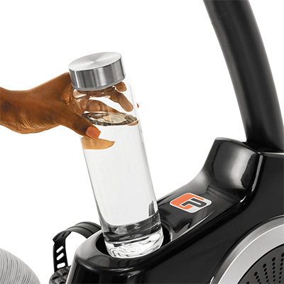 Close-up of a hand placing a water bottle into the ProForm 325 CSX Recumbent Bike cup holder 