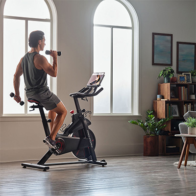 Model doing bicep curls on the ProForm Pro Trainer 500 Bike during an iFIT workout.