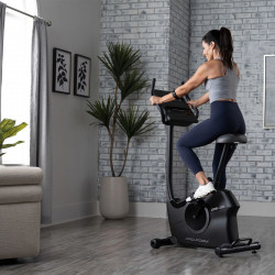 Model riding the ProForm 225 CSX Upright Exercise Bike in a home workout space