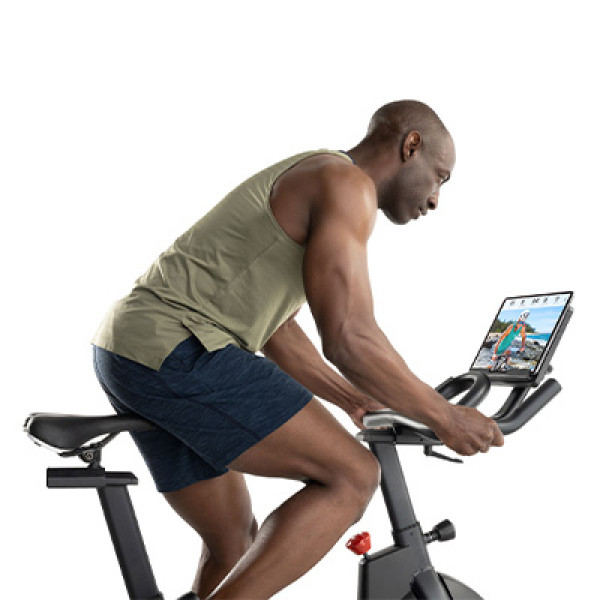 Model cycling on the ProForm Sport CX Bike while viewing iFIT workout on tablet