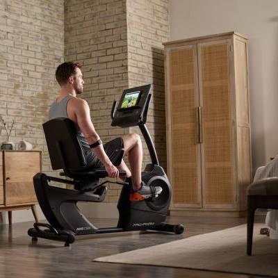 Rear angled view of a user cycling on the ProForm 325 CSX Recumbent Bike in a home workout space 