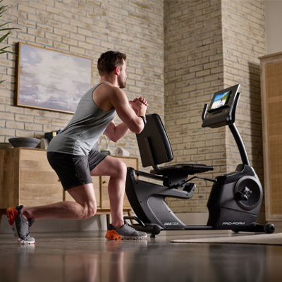 Person performing a lunge exercise beside the ProForm 325 CSX Recumbent Bike  