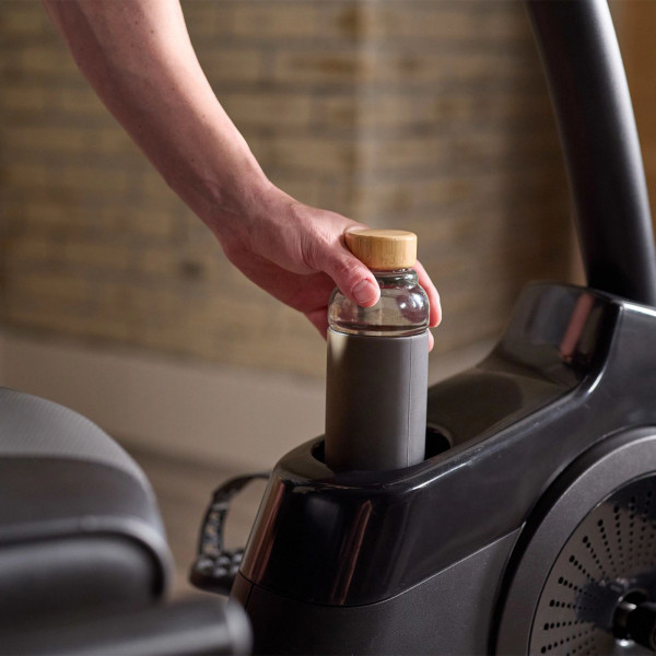 Close-up of a hand placing a water bottle into the cup holder on the ProForm 325 CSX Recumbent Bike