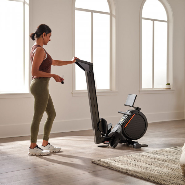 Lifestyle image of the ProForm 550R Rower in a home setting. The model is folding the rower.