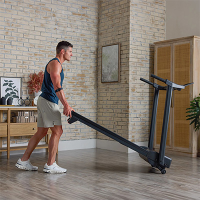 Model rolling the ProForm Sport Treadmill across home gym floor 