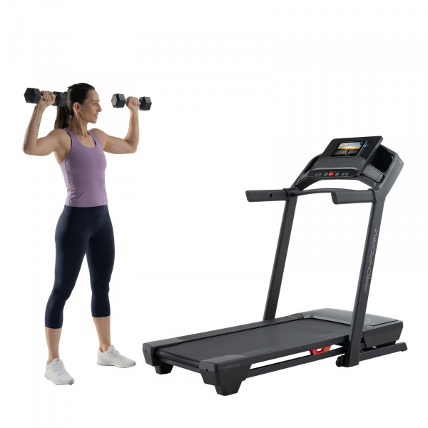 Model doing dumbbell shoulder press beside the ProForm Carbon TL Treadmill