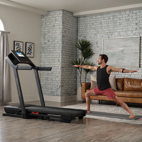 Model doing yoga beside the ProForm Carbon TLS Treadmill