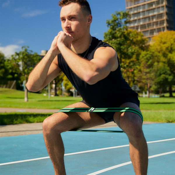 User squatting outdoors with the green PTP MicroBand X