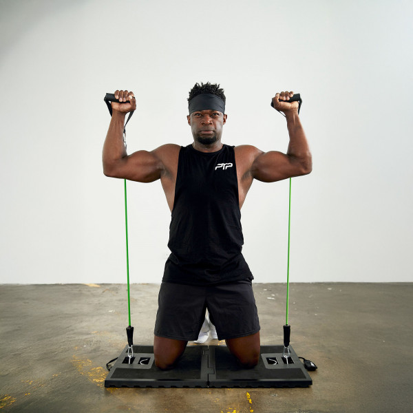User doing overhead press on knees indoors