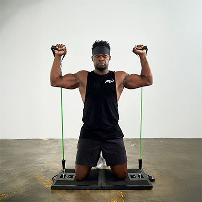 User doing overhead press on knees indoors