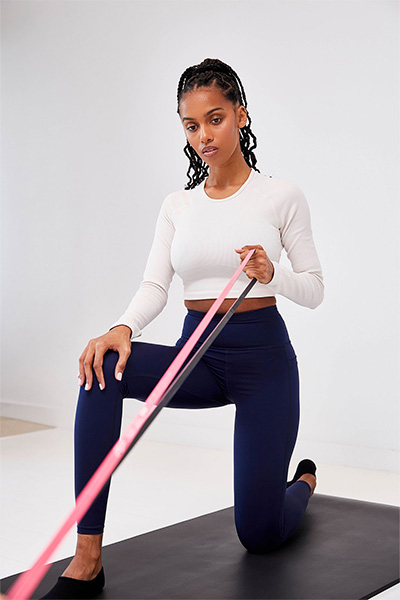 User doing kneeling row exercise with pink (ultra light resistance) SuperBand