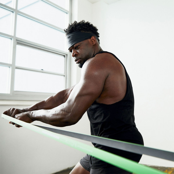 User doing standing row exercise with green (medium resistance) SuperBand