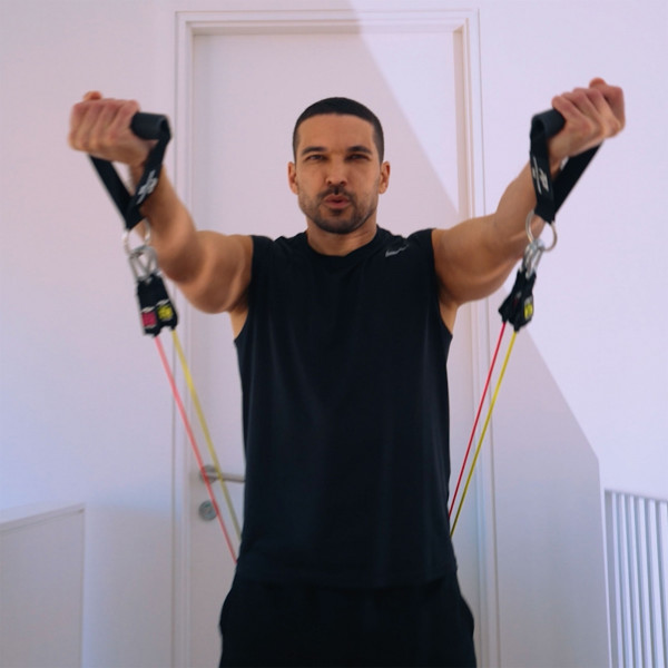 Person using PTP Total Resistance Gym for front raise indoors