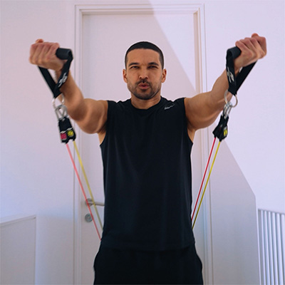 Person using PTP Total Resistance Gym for front raise indoors