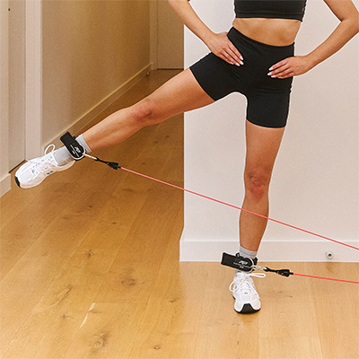 Person using PTP Total Resistance Gym for standing leg abduction indoors