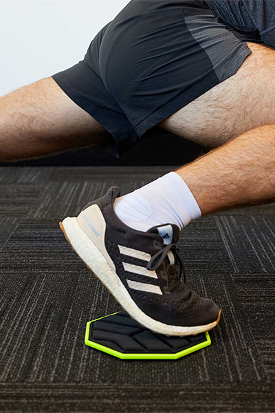 A close-up image of a foot using the PTP Core Slider during a sliding lunge exercise.
