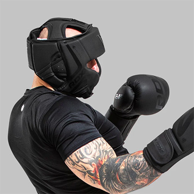 Grey background side image of a model wearing the RDX Noir Head Guard