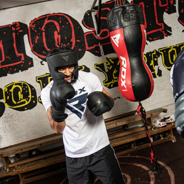 A model in a boxing gym wearing the RDX Noir Head Guard