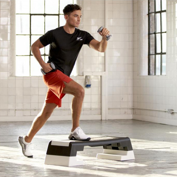 Step-up with dumbbells on the white Reebok Step