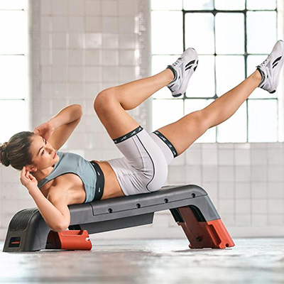 Model doing incline bench triceps work on the blue Reebok Deck