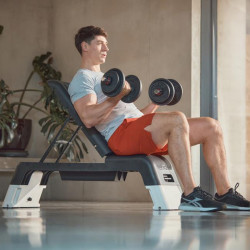 Model doing seated dumbbell curls on the white Reebok Deck