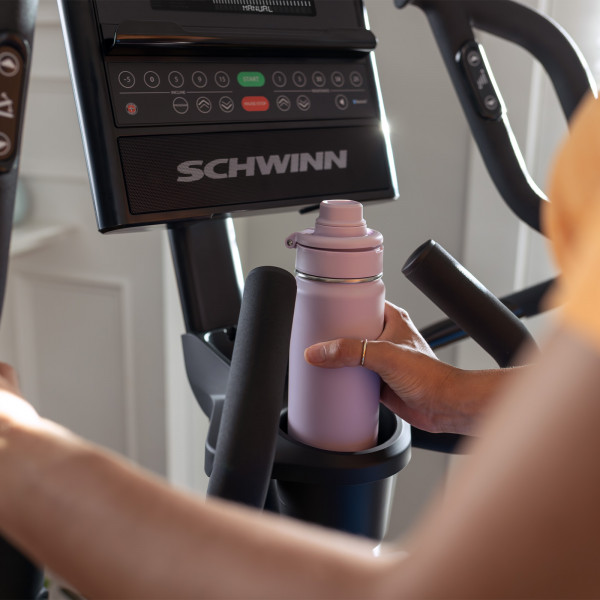 Model placing a water bottle in the holder on the Schwinn 590E Elliptical