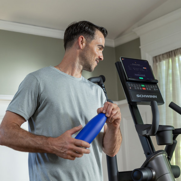 Model holding a water bottle next to the Schwinn 590E Elliptical