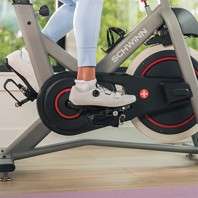 Closeup of the dual-sided pedals on the Schwinn IC3.5 Indoor Cycle with the model's cycling shoes clipped into the SPD pedals  