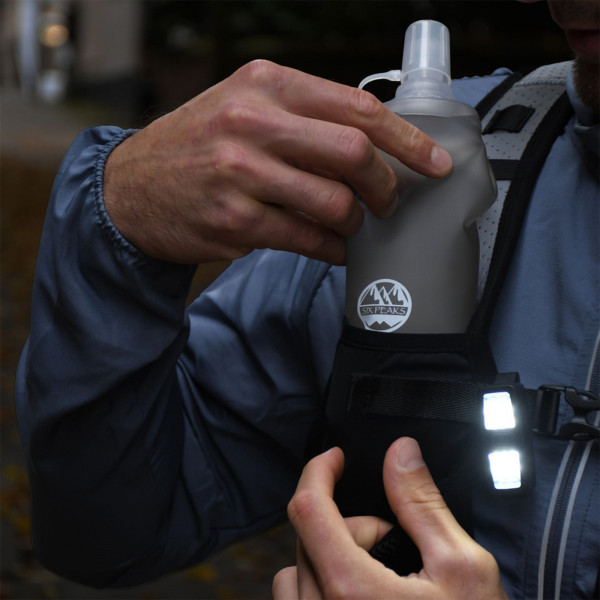 Person placing bottle into the Six Peaks Hydration Running Vest in black colour (XS/S)