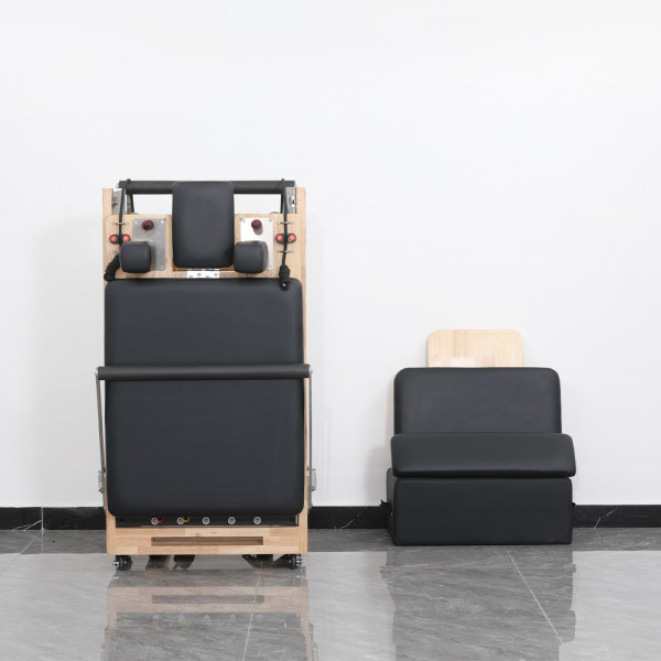 Front view of the Skelcore Foldable Reformer - Oak folded with sitting box nearby